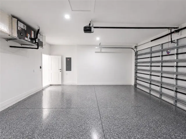 Garage featuring a speckled epoxy floor, white painted walls, recessed lighting, and a white interior door