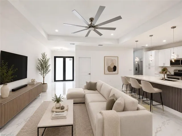Open-concept living space featuring a tray ceiling, recessed lighting, and a modern ceiling fan