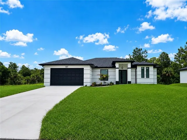 Contemporary architectural style featuring a white stucco exterior with black trim accents, a dark shingle roof, and a two-car garage