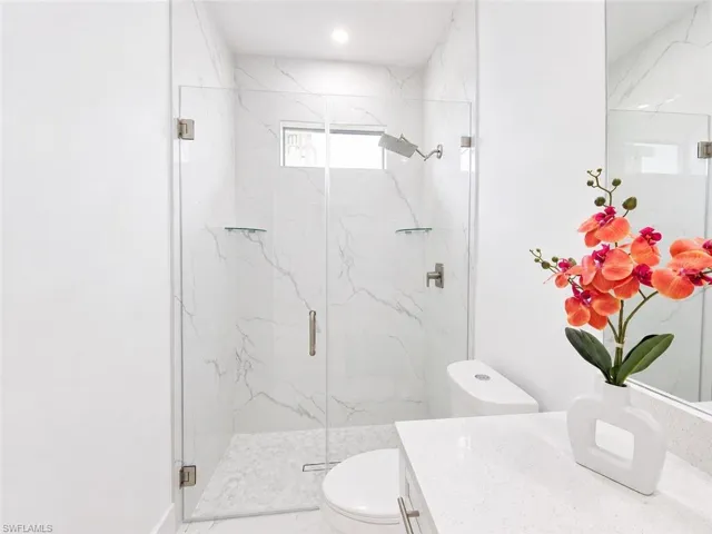 Contemporary bathroom featuring a frameless glass shower enclosure with white marble-look tile surround and a tiled shower pan