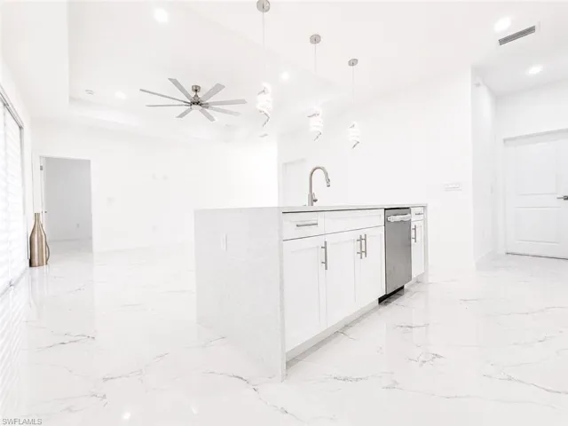 Modern kitchen island featuring a waterfall countertop, undermount sink with gooseneck faucet, and white shaker cabinetry