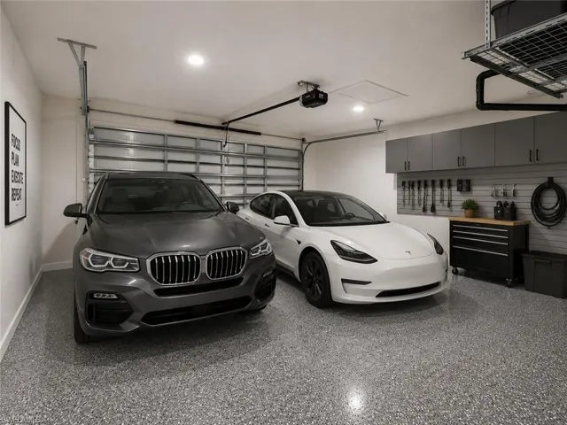 Two-car garage featuring a speckled epoxy floor, overhead storage rack, wall-mounted cabinetry, and a slatwall organization system