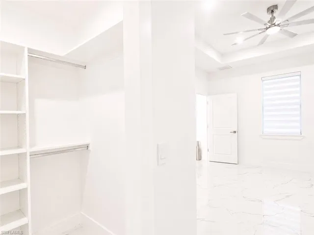 Walk-in closet featuring built-in shelving, hanging rods, and sleek white walls