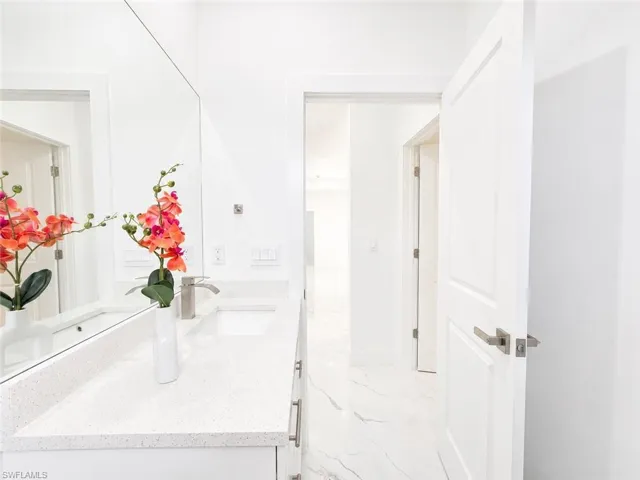 White vanity with a light speckled countertop, undermount sink, and brushed nickel faucet
