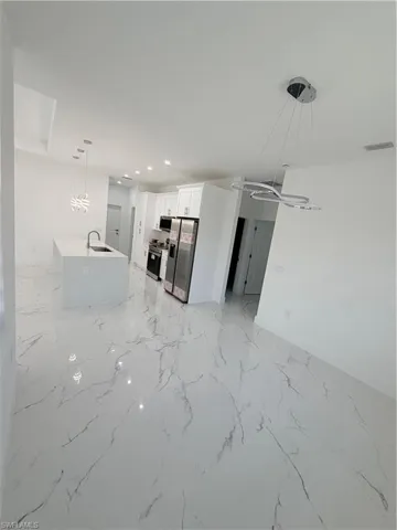 Kitchen featuring hanging light fixtures, open floor plan, light marble finish flooring, stainless steel appliances, and recessed lighting