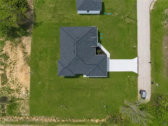 Newly constructed residence featuring a dark shingle roof and a light-colored driveway