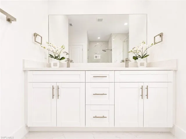 Dual vanity featuring white shaker cabinetry, brushed nickel hardware, and a light-colored solid surface countertop