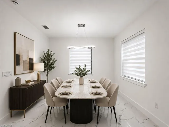 Dining area featuring white walls, large windows with horizontal blinds, and a contemporary linear chandelier