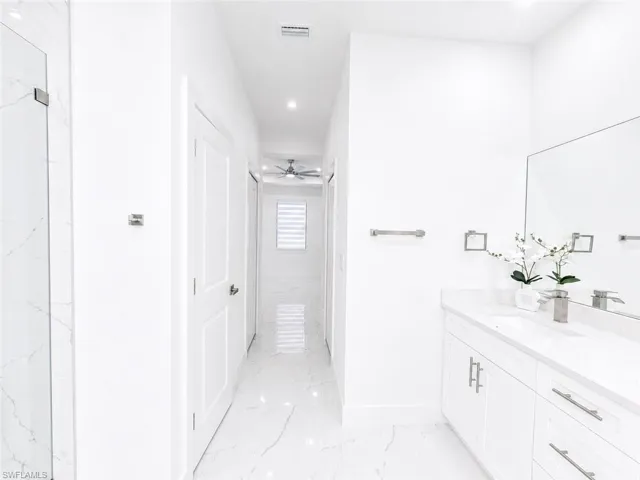 Modern bathroom featuring a white floating vanity with a light-toned countertop, a large wall-mounted mirror, and sleek brushed nickel hardware