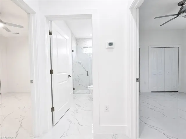 Hallway featuring white panel doors and marble-look tile flooring