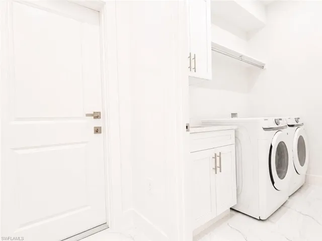 Dedicated laundry area featuring white cabinetry with silver-tone hardware, a white countertop, and shelving with a hanging rod