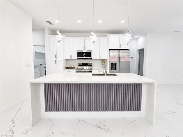 Kitchen island featuring a waterfall countertop and a ribbed panel base