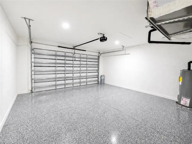 Spacious garage featuring a durable epoxy chip flooring, automatic garage door opener, recessed lighting, and white painted walls