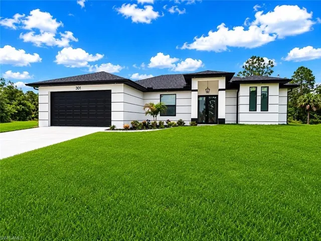 Contemporary-style residence featuring a prominent black garage door, a paved driveway, and an expansive green lawn