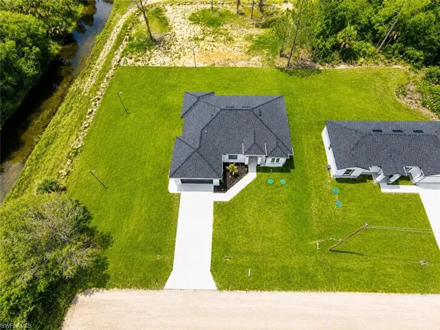 Aerial perspective showcasing a single-story residence with a dark shingle roof and a concrete driveway