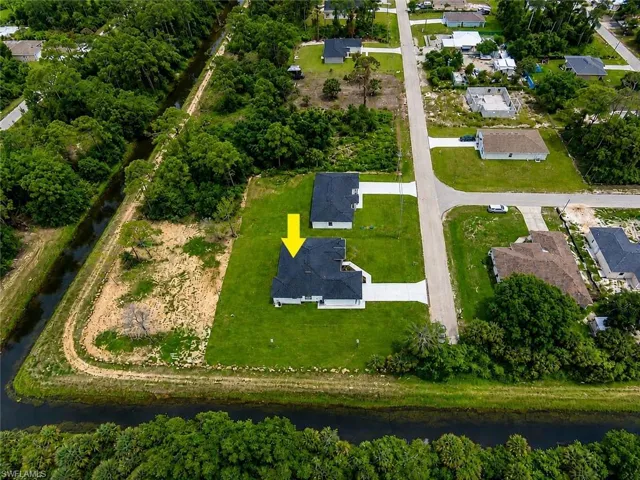 Aerial perspective showcasing a single-story residence with a dark shingle roof, green lawn, and a concrete driveway