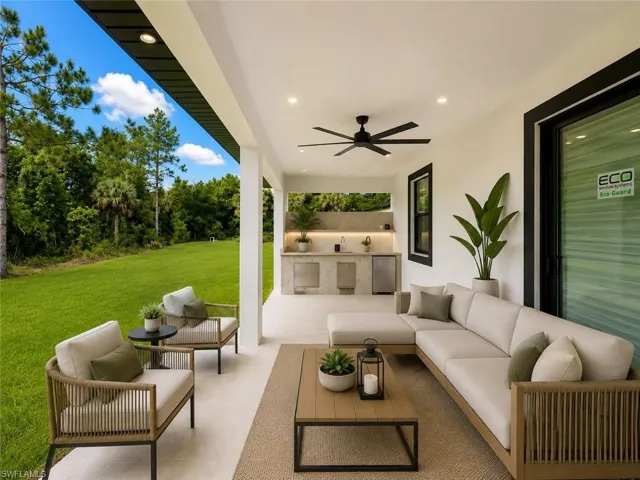 Expansive covered patio featuring an outdoor kitchen with built-in cabinetry, an integrated sink, and a compact refrigerator