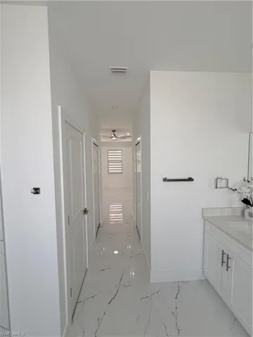 Full bath with vanity, light marble finish flooring, a shower stall, and ceiling fan