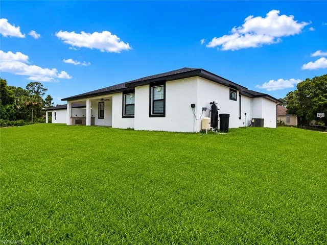 Expansive green lawn with a contemporary white stucco exterior and dark trim windows
