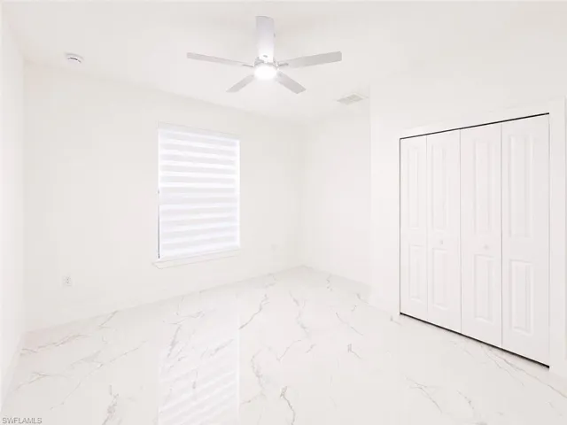 Bright room featuring white walls, large format tile flooring, a contemporary ceiling fan, and a window with horizontal blinds