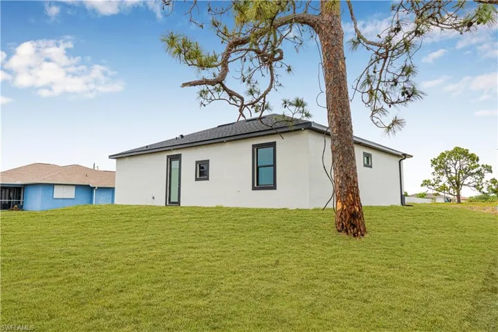 Back of house with stucco siding and a lawn