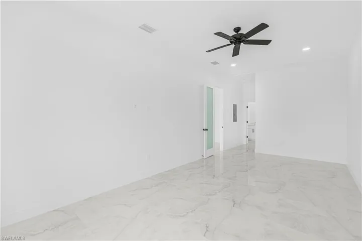 Empty room with marble finish floor, baseboards, ceiling fan, and visible vents