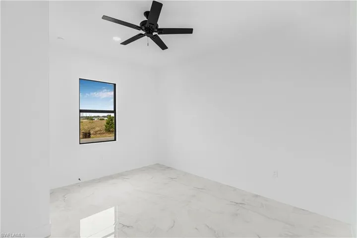 Empty room featuring baseboards, marble finish floor, and a ceiling fan