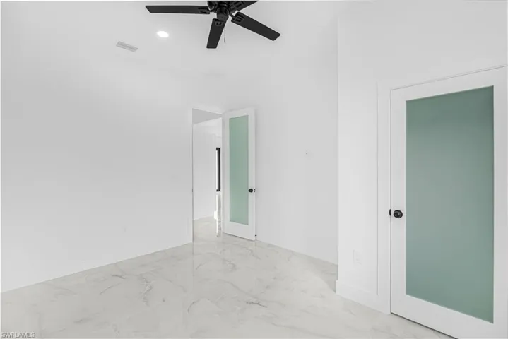 Spare room featuring marble finish floor, baseboards, ceiling fan, and visible vents