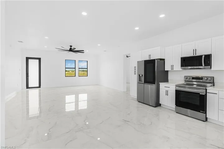 Kitchen featuring marble finish floor, white cabinets, stainless steel appliances, and light countertops