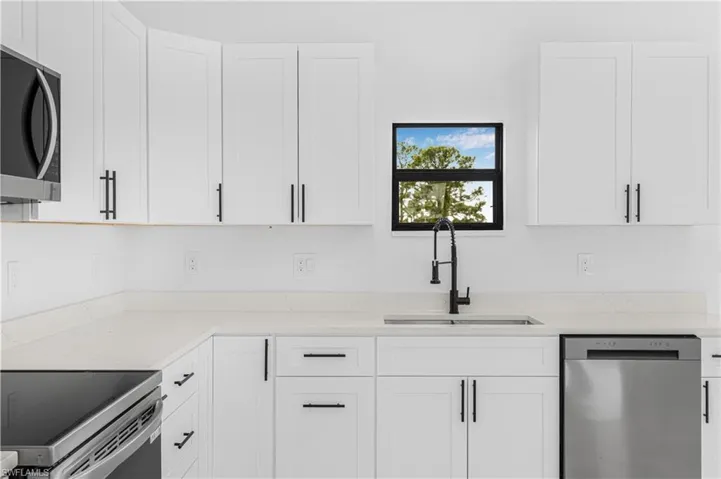 Kitchen featuring a sink, white cabinets, and appliances with stainless steel finishes