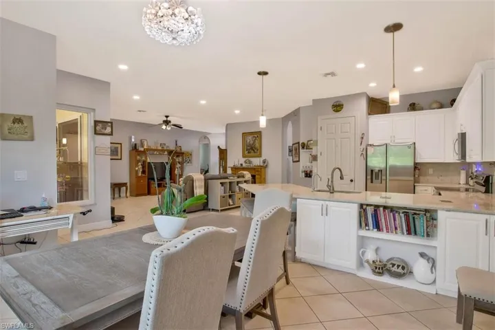 Tiled dining space featuring sink and ceiling fan with notable chandelier