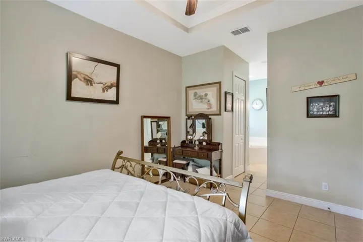 Tiled bedroom with a closet, ceiling fan, and ensuite bathroom