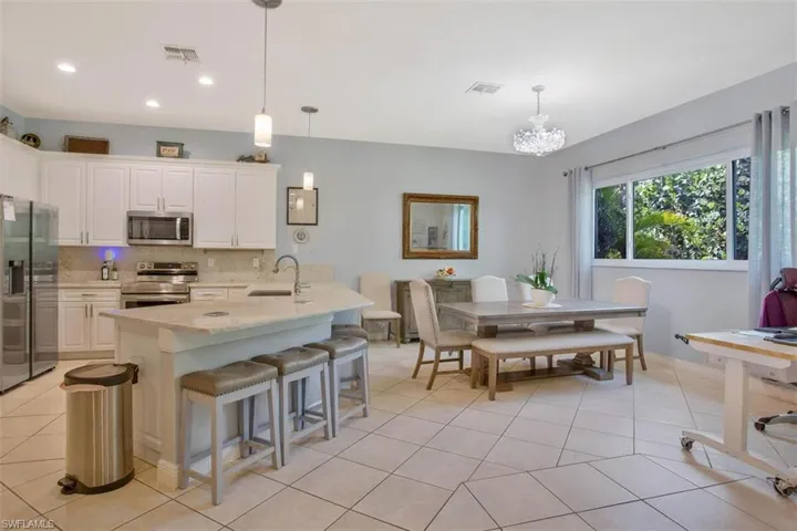 Kitchen with white cabinetry, decorative light fixtures, stainless steel appliances, and sink