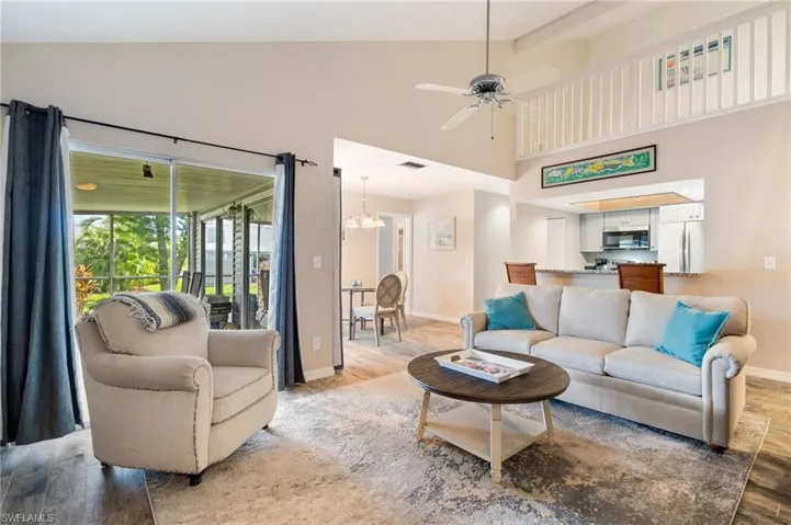 Living area featuring wood finished floors, high vaulted ceiling, beamed ceiling, a ceiling fan, and a chandelier