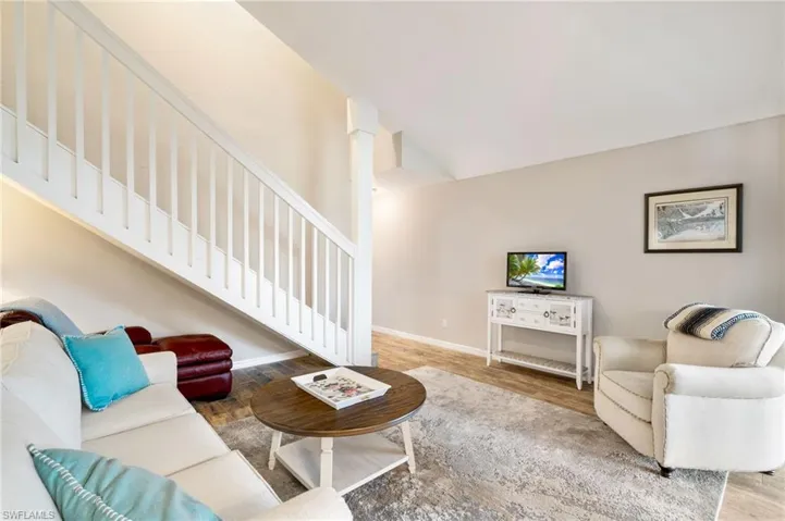 Living area with wood finished floors, stairway, and vaulted ceiling