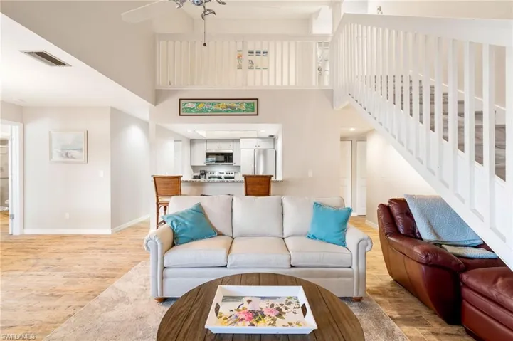 Living room featuring a high ceiling, light wood finished floors, and a ceiling fan
