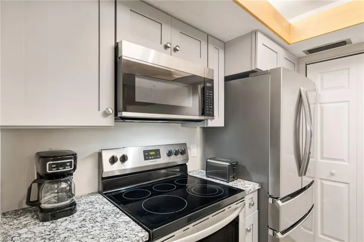 Kitchen with stainless steel appliances and light stone counters