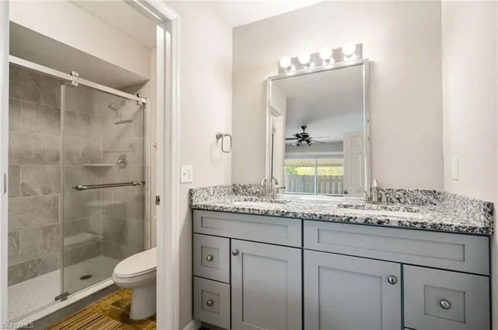 Full bathroom with a stall shower, double vanity, and a ceiling fan