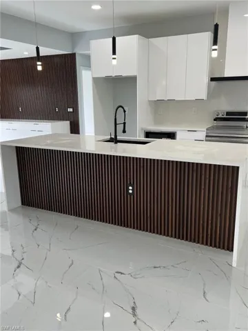 Kitchen featuring hanging light fixtures, modern cabinets, white cabinets, and light countertops