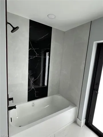 Bathroom with shower / bath combination and marble finish floor