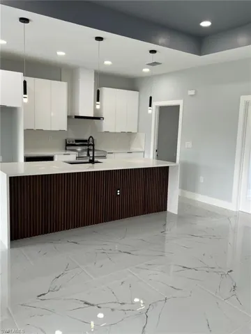Kitchen with white cabinets, light countertops, decorative light fixtures, and modern cabinets