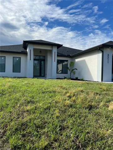 Back of house with a yard and stucco siding