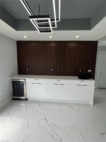 Bar with baseboards, marble finish floor, wine cooler, and recessed lighting
