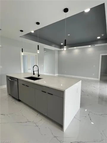 Kitchen with a sink, pendant lighting, dishwasher, and gray cabinetry