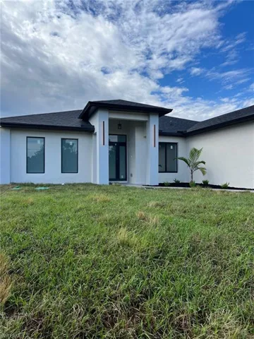Rear view of property with a yard and stucco siding