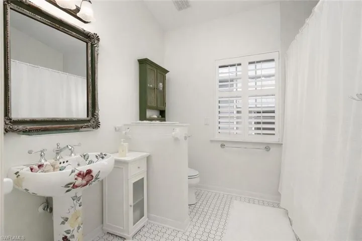Bathroom with curtained shower and lofted ceiling