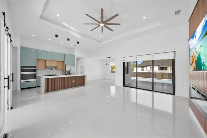 Unfurnished living room featuring a barn door, recessed lighting, a ceiling fan, a chandelier, and a raised ceiling