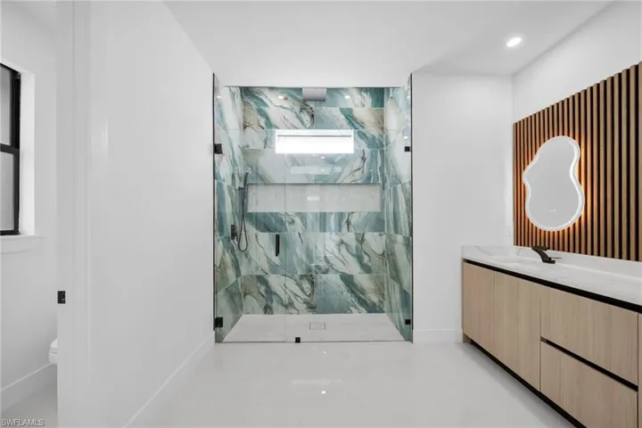 Bathroom featuring a marble finish shower and vanity