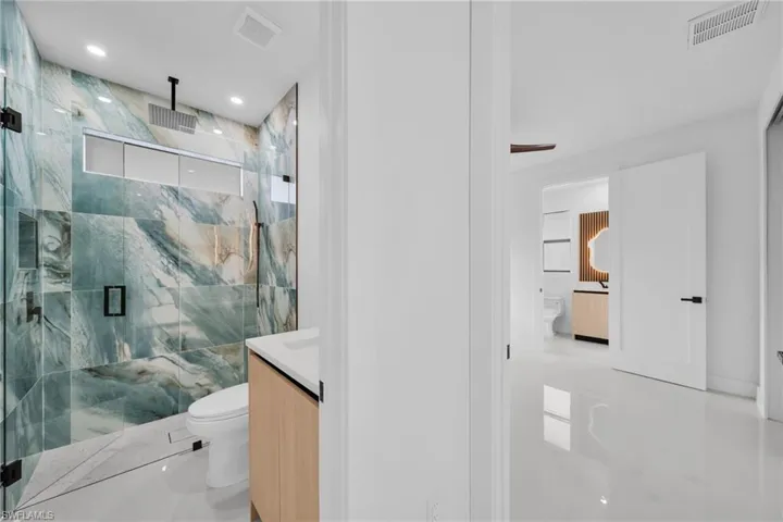 Bathroom featuring a marble finish shower and vanity