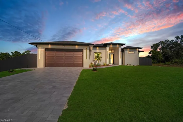 View of front of home with decorative driveway, stucco siding, and an attached garage